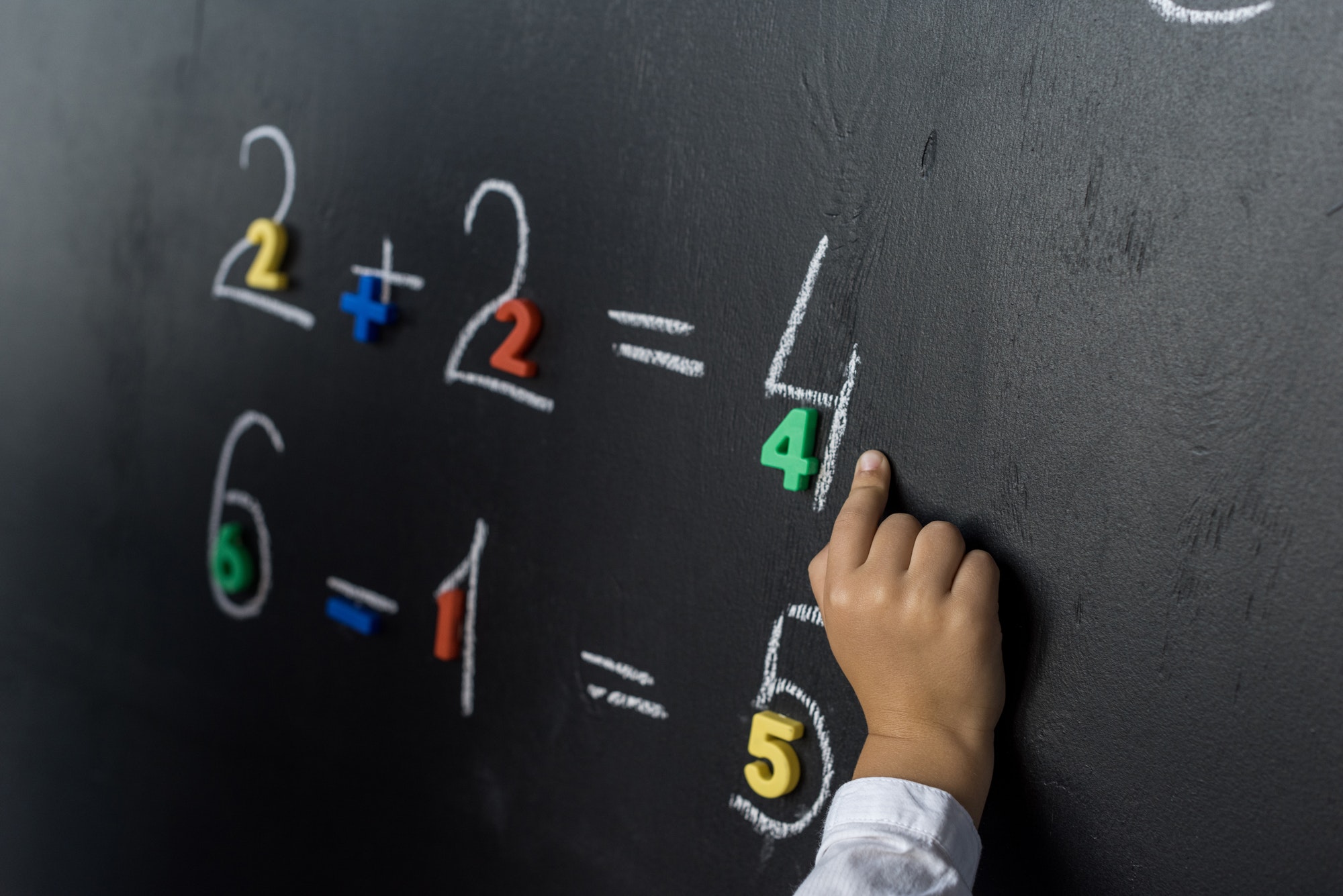 cropped shot of child studying numbers on chalkboard