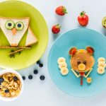 flat lay with creatively styled children's breakfast with berries and kiwi