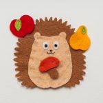 Funny felt toy. Toy hedgehog with red apple, yellow pear and mushroom in paws. Handmade toy.