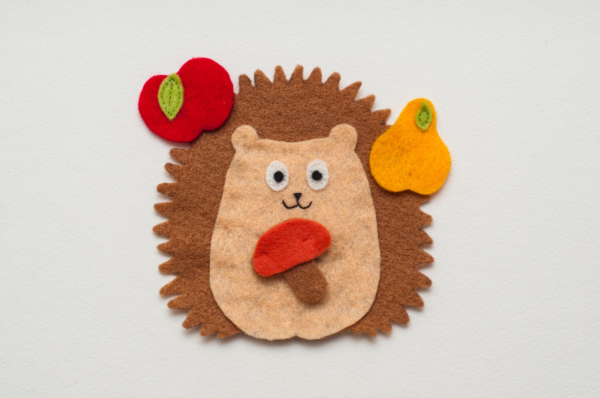 Funny felt toy. Toy hedgehog with red apple, yellow pear and mushroom in paws. Handmade toy.