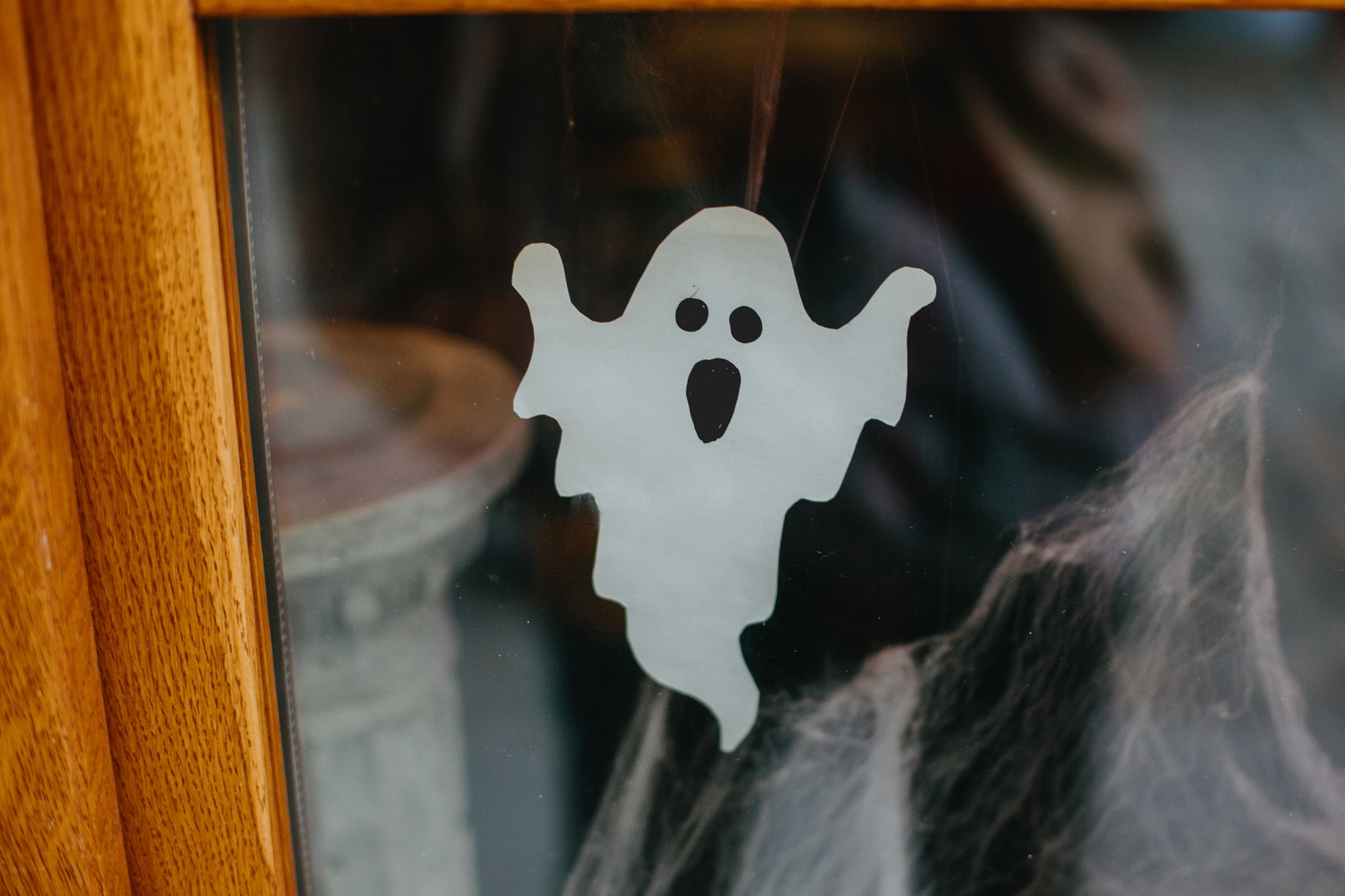 Paper cut ghost and cobweb on door or window at store