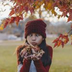 Young girl holding autumn leaves and making a funny face