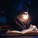 An open book with lighting by a star inside a lightbulb