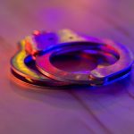 Police raid at night and you are under arrest of handcuffs with police with the flashing red and blu